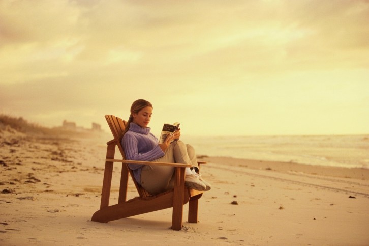 Reading in chair on beach at sunset